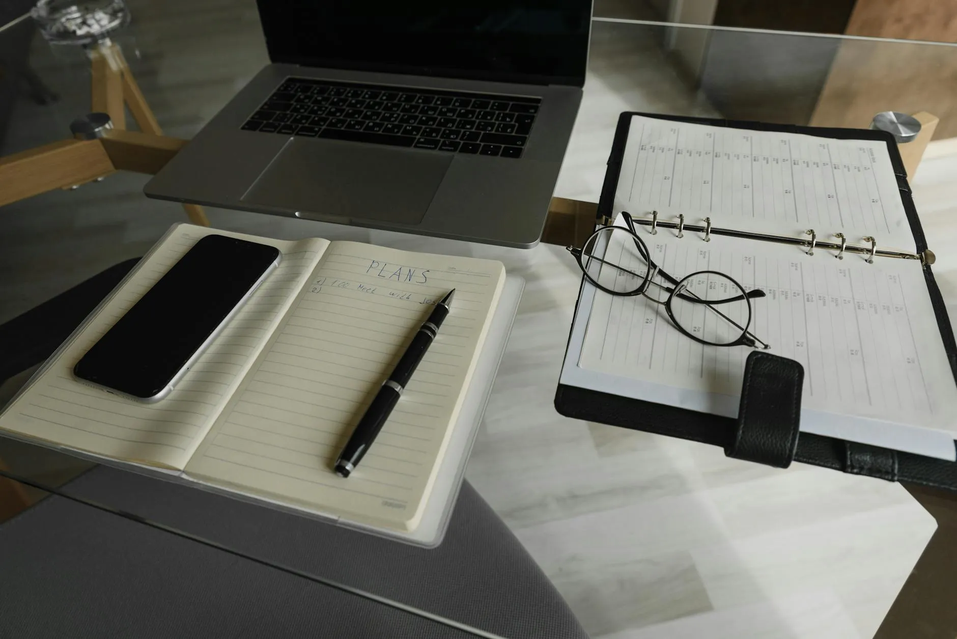 Empresário organizado em mesa de trabalho com computador e agenda, expressão tranquila