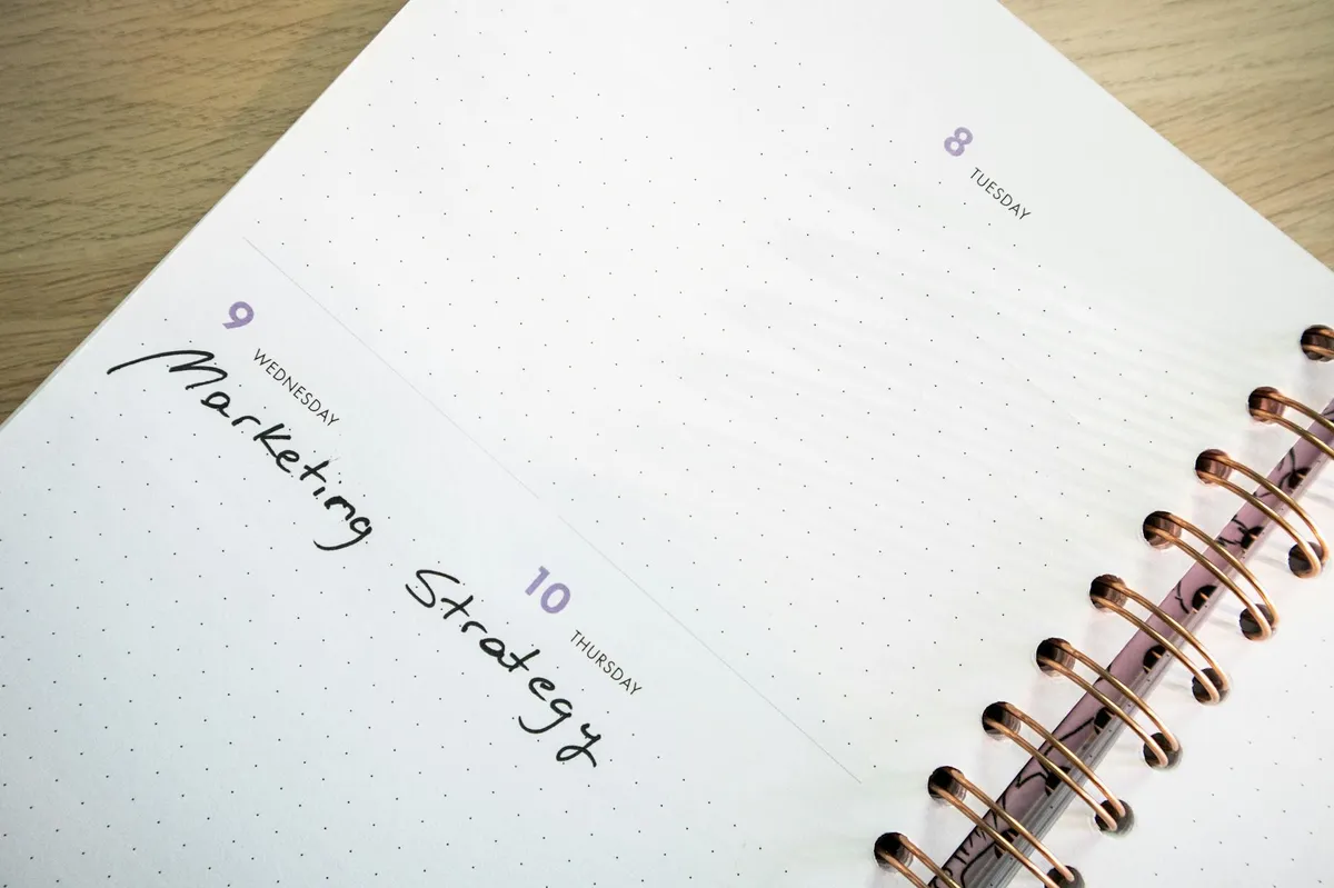 Empresário anotando indicadores e metas em caderno ao lado de notebook