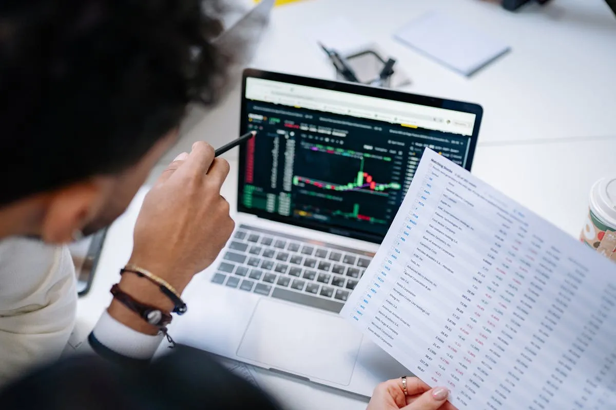 Empresário revisando planilha financeira em notebook com caneta na mão sobre mesa de escritório