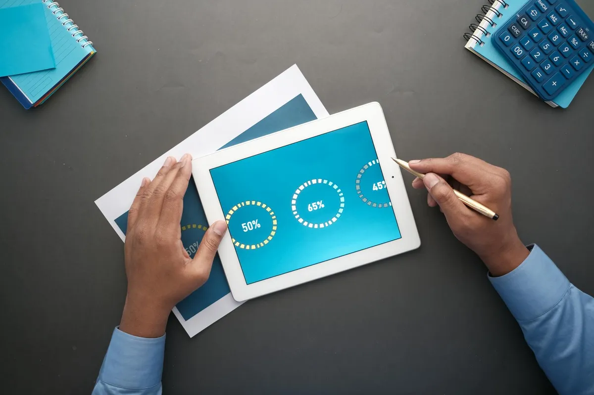 Dono de negócio analisando dados em tablet com bloco de notas ao lado