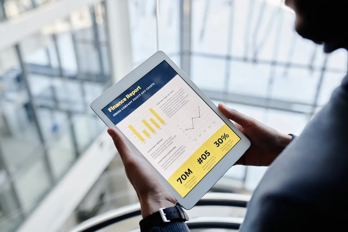 Empresário consultando relatório em tablet com calendário ao fundo em escritório claro