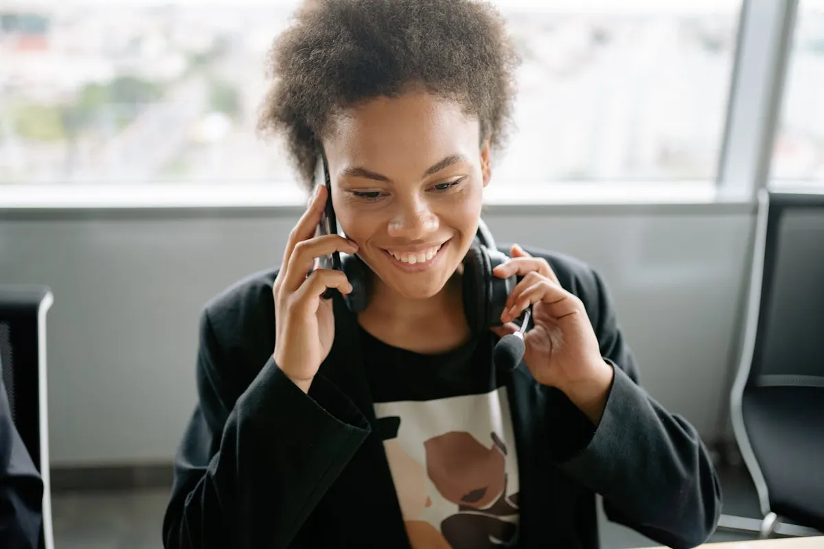 Atendente de pequena empresa ao telefone com computador aberto na sua frente
