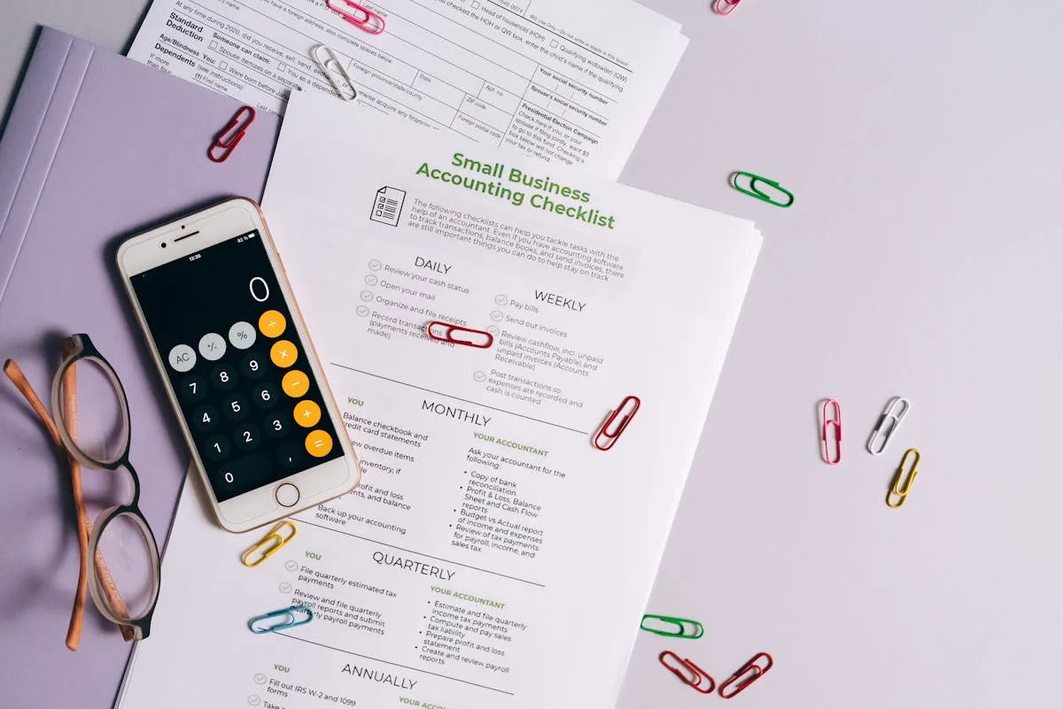 Dono de pequena empresa analisando planilha financeira com calculadora e caderno na mesa