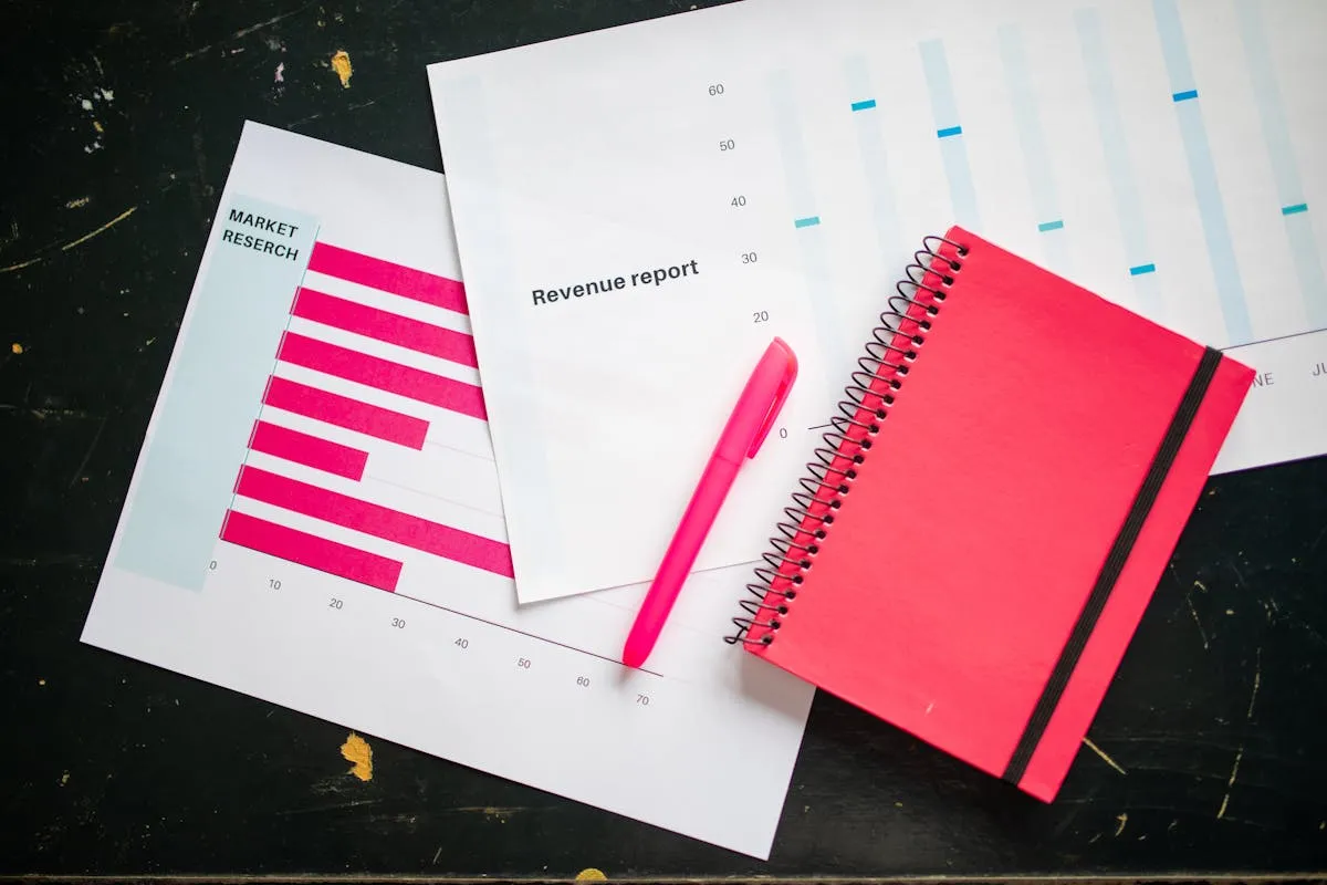 Caderno de planejamento aberto com caneta ao lado de notebook fechado sobre mesa de madeira