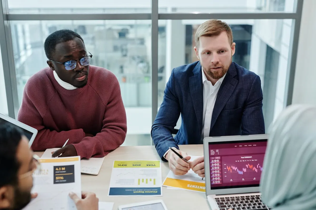 Empresário e colaborador analisando relatório em laptop na mesa de trabalho