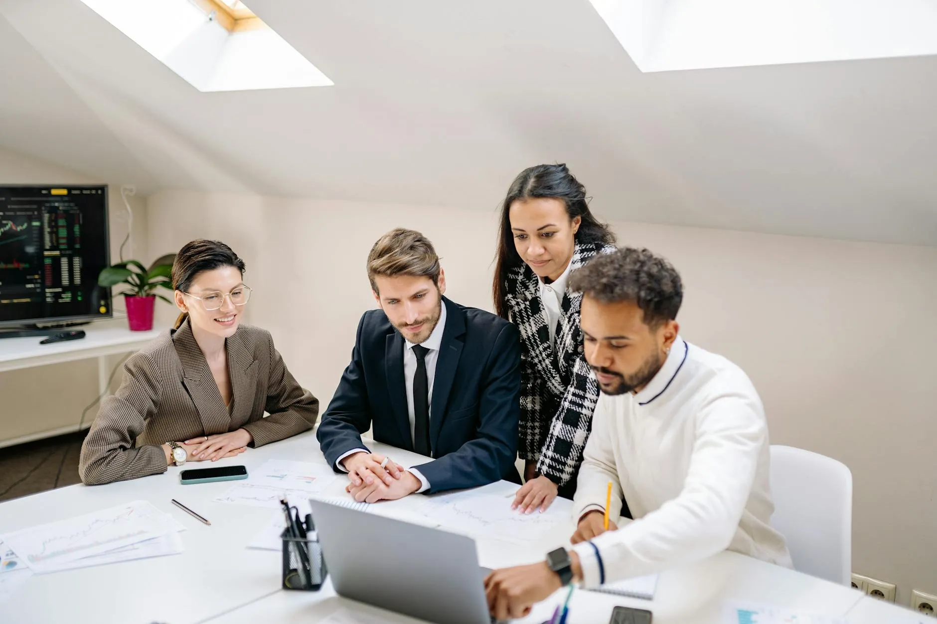 Empresário em reunião com equipe ao redor de mesa com laptops abertos
