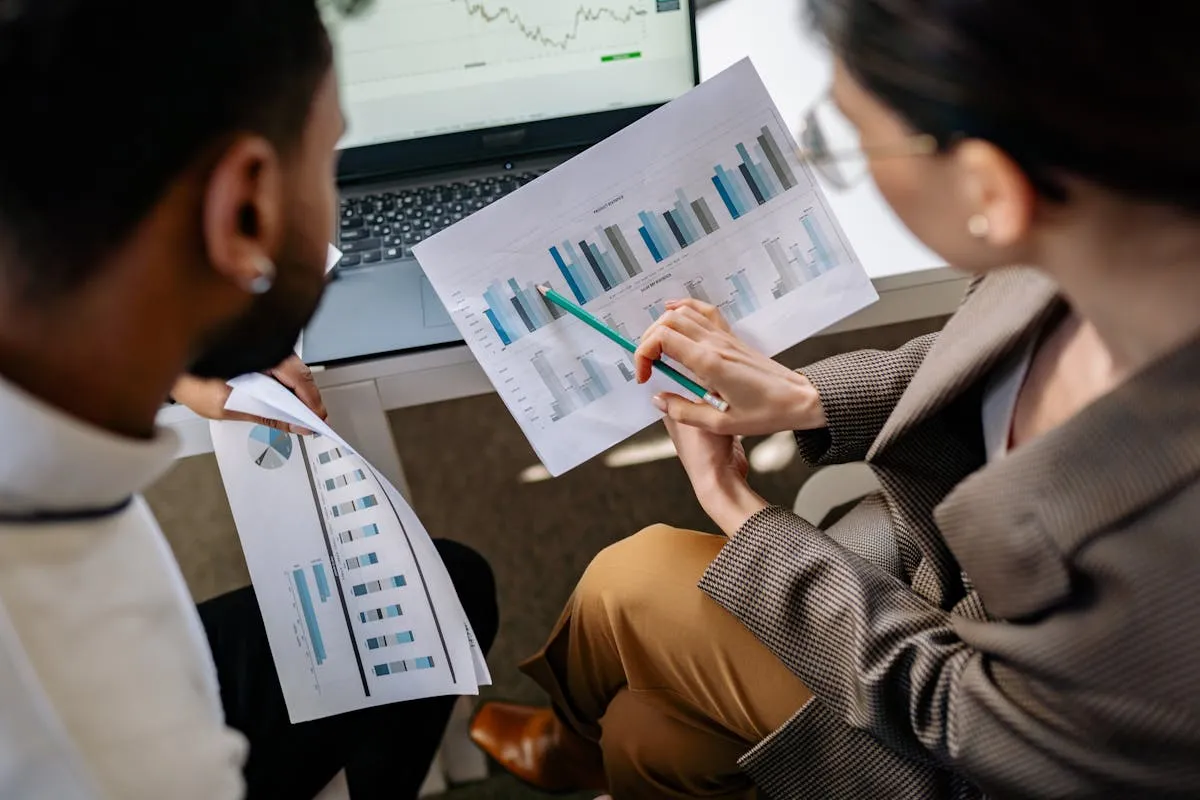 Reunião de pequena equipe em torno de mesa discutindo dados em notebook