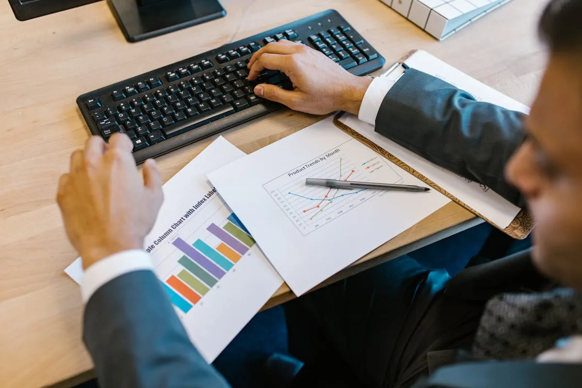 Empresário olhando para gráficos e relatórios em um computador em seu escritório