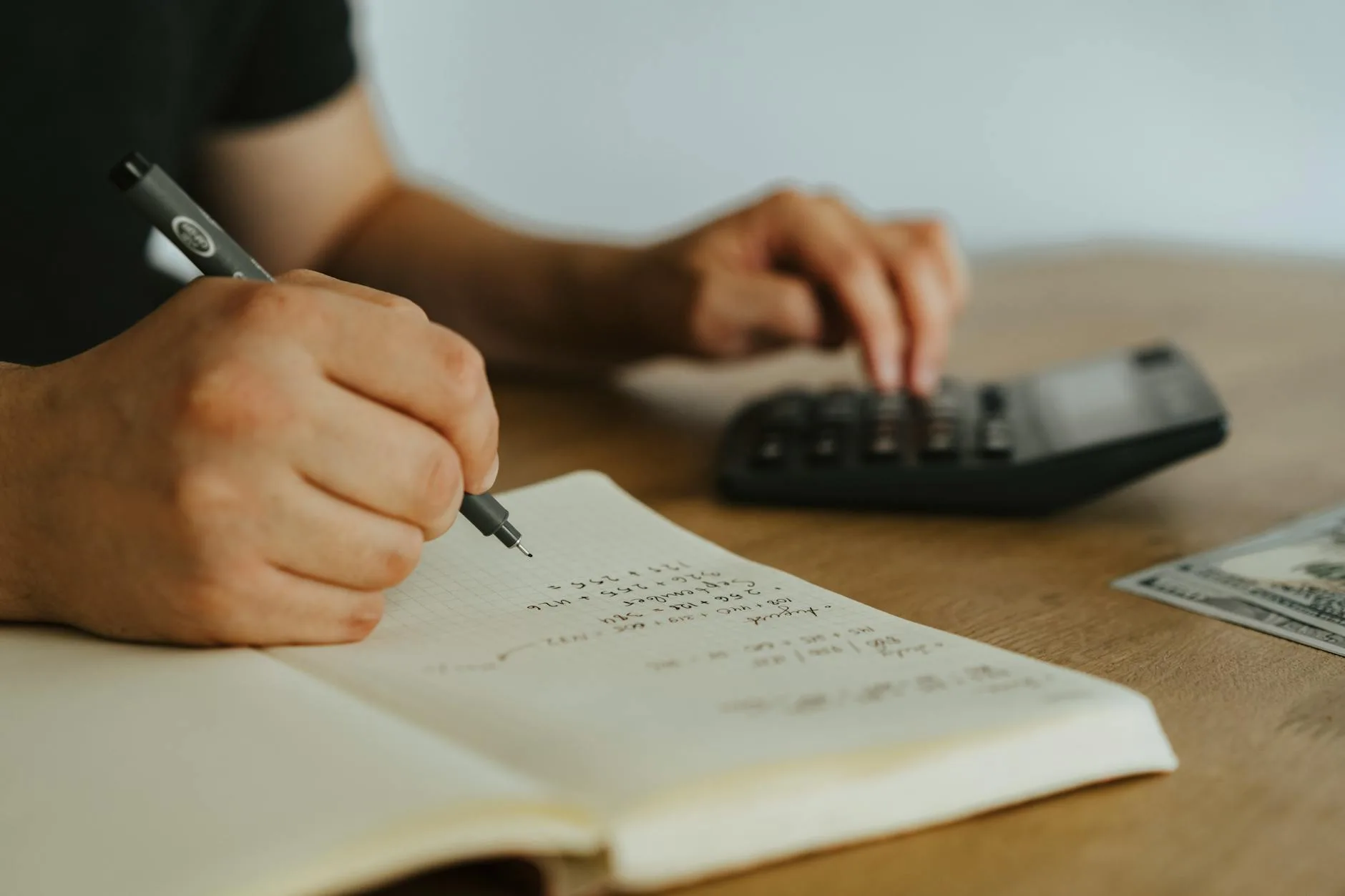 Empresário avaliando custos no notebook com calculadora e papéis na mesa