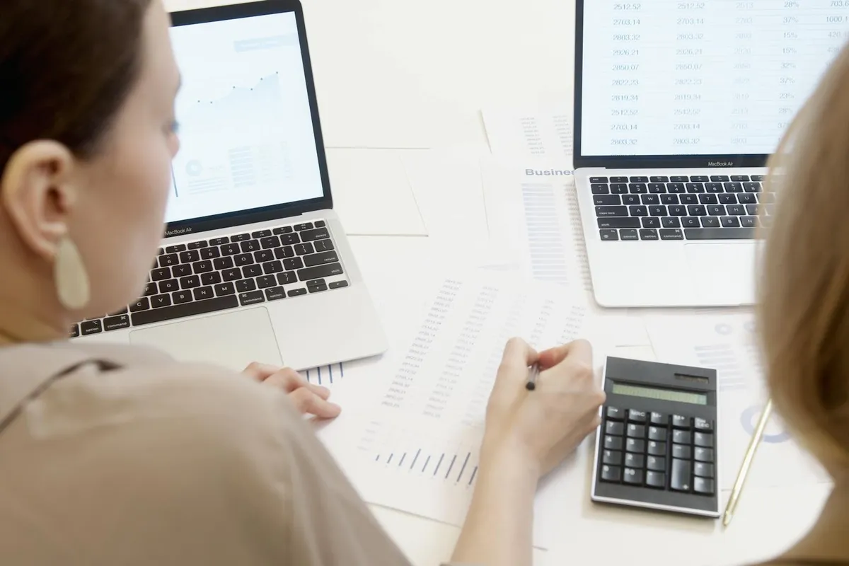 Dono de pequena empresa analisando planilha de metas no computador com expressão satisfeita