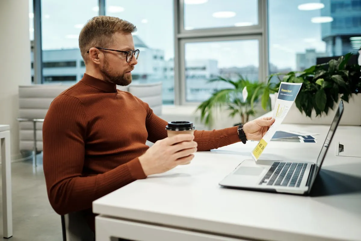 Dono de negócio analisando gráficos e relatórios no notebook em escritório simples