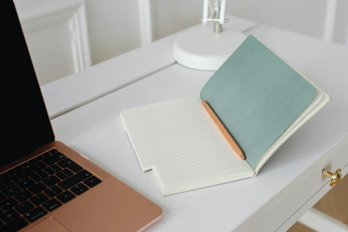 Dono de pequeno negócio escrevendo em caderno ao lado de um computador simples