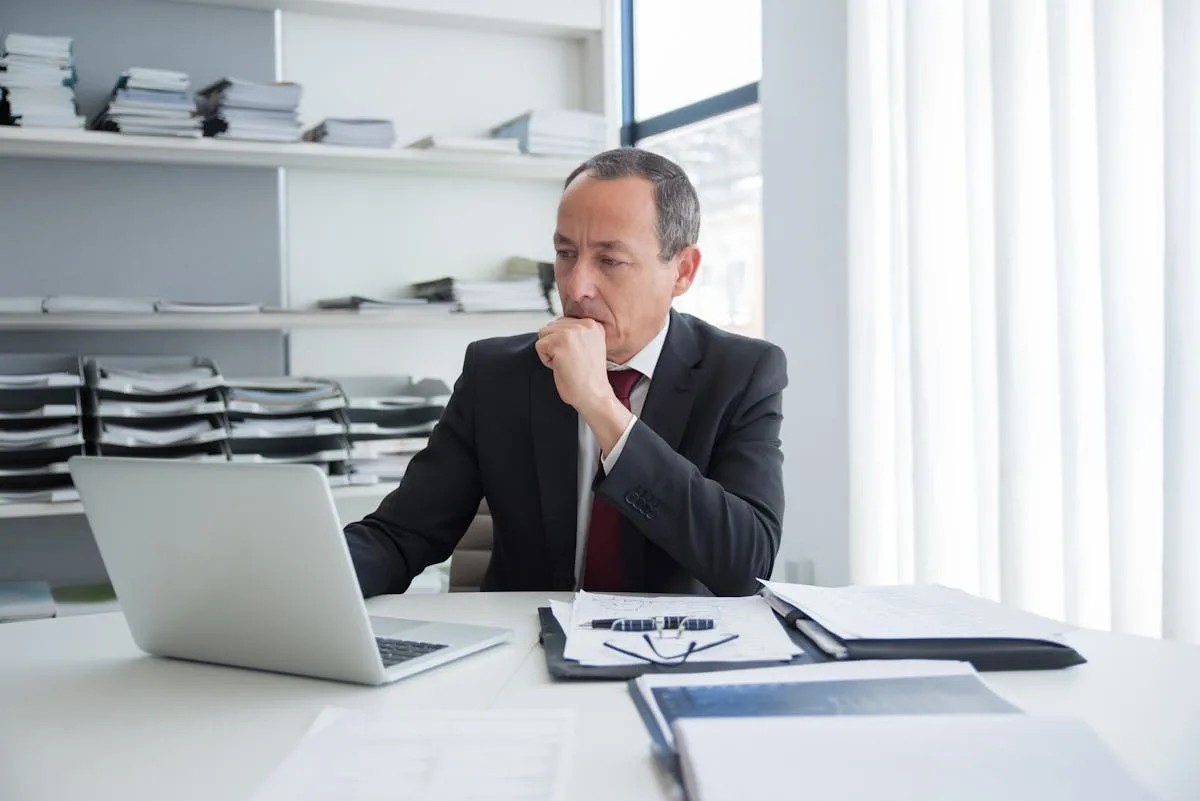 Empresário pensativo analisando opções de negócio em frente ao computador